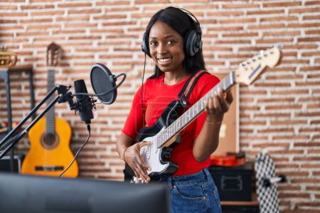 Photo for Young african american woman artist singing song playing electrical guitar at music studio - Royalty Free Image