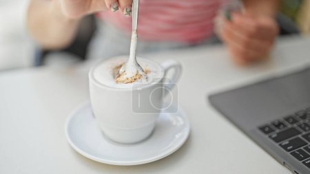 Téléchargez les photos : Jeune femme blonde remuer le café à la terrasse du café - en image libre de droit