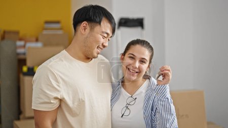 Foto de Hombre y mujer pareja abrazándose unos a otros sosteniendo llaves en nuevo hogar - Imagen libre de derechos
