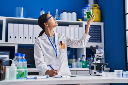 Photo for Young african american woman scientist measuring liquid at laboratory - Royalty Free Image