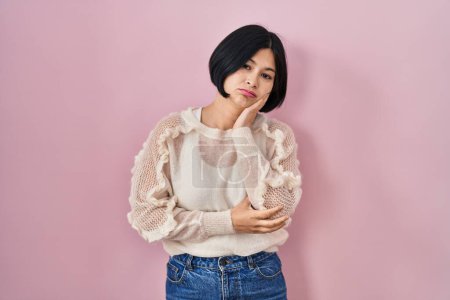 Téléchargez les photos : Jeune femme asiatique debout sur fond rose pensant à la recherche fatigué et ennuyé avec des problèmes de dépression avec les bras croisés. - en image libre de droit