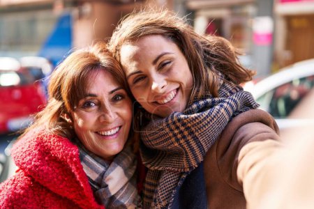 Téléchargez les photos : Two women mother and daughter make selfie by camera at street - en image libre de droit
