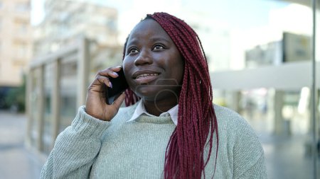 Téléchargez les photos : Femme africaine avec des cheveux tressés parlant au téléphone dans la rue - en image libre de droit