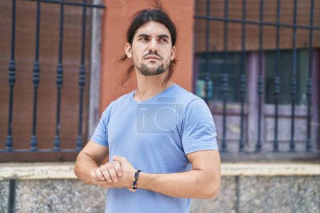 Photo for Young hispanic man looking to the side with relaxed expression at street - Royalty Free Image