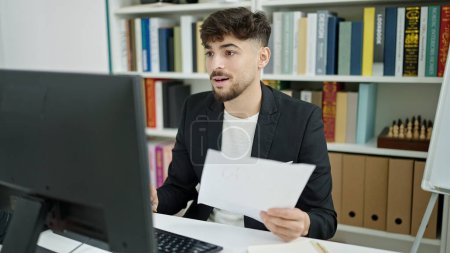 Photo for Young arab man student using computer reading document at university classroom - Royalty Free Image