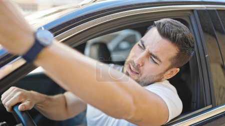 Téléchargez les photos : Jeune homme hispanique conduisant une voiture dans la rue - en image libre de droit