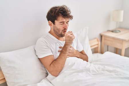 Photo for Young man sitting on bed coughing at bedroom - Royalty Free Image