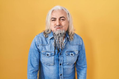 Photo for Middle age man with grey hair standing over yellow background puffing cheeks with funny face. mouth inflated with air, crazy expression. - Royalty Free Image