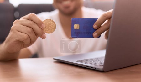 Téléchargez les photos : Jeune homme hispanique tenant litecoin crypto monnaie et carte de crédit à la maison - en image libre de droit