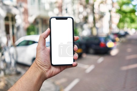 Téléchargez les photos : Homme tenant smartphone montrant écran blanc vierge au parking - en image libre de droit