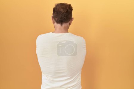 Téléchargez les photos : Middle age man with beard standing over yellow background standing backwards looking away with crossed arms - en image libre de droit