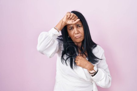 Téléchargez les photos : Femme hispanique mature debout sur fond rose touchant le front pour la maladie et la fièvre, la grippe et le rhume, le virus malade - en image libre de droit