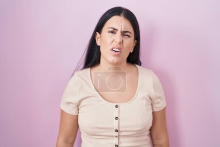 Photo for Young hispanic woman standing over pink background looking sleepy and tired, exhausted for fatigue and hangover, lazy eyes in the morning. - Royalty Free Image
