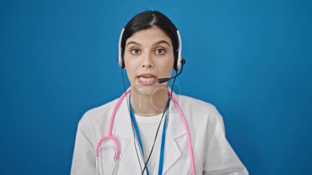 Photo for Young beautiful hispanic woman doctor smiling confident having online medical consultation over isolated blue background - Royalty Free Image