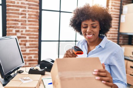 Téléchargez les photos : Africaine américaine femme commerce électronique travailleur d'affaires numérisation paquet au bureau - en image libre de droit
