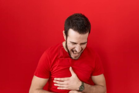 Téléchargez les photos : Jeune homme hispanique portant casual t-shirt rouge souriant et riant dur à haute voix parce que drôle blague folle avec les mains sur le corps. - en image libre de droit