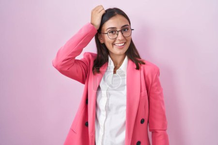 Foto de Joven mujer hispana vestida con ropa de negocios y gafas sonriendo confiado tocando el cabello con la mano hacia arriba gesto, posando atractivo y de moda - Imagen libre de derechos