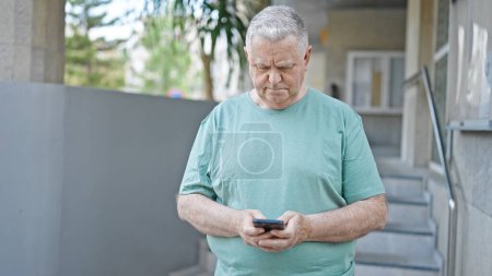 Photo for Middle age grey-haired man using smartphone with serious expression at street - Royalty Free Image