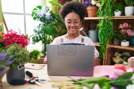 Photo for African american woman florist smiling confident using laptop at flower shop - Royalty Free Image