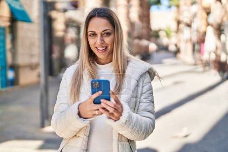 Photo for Young woman smiling confident using smartphone at street - Royalty Free Image