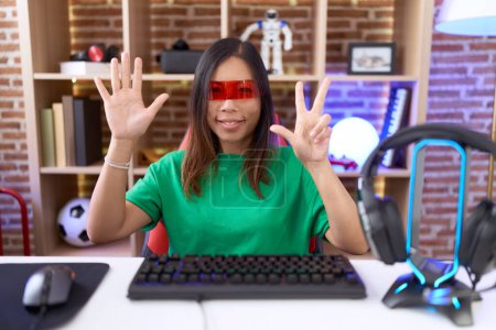 Photo for Middle age chinese woman wearing virtual reality glasses showing and pointing up with fingers number eight while smiling confident and happy. - Royalty Free Image