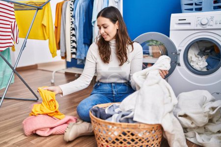 Photo for Young beautiful hispanic woman smiling confident washing clothes at laundry room - Royalty Free Image
