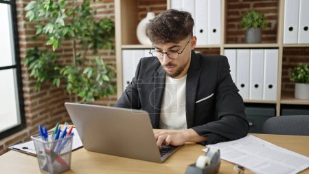 Foto de Hombre árabe joven trabajador de negocios utilizando el ordenador portátil de trabajo en la oficina - Imagen libre de derechos