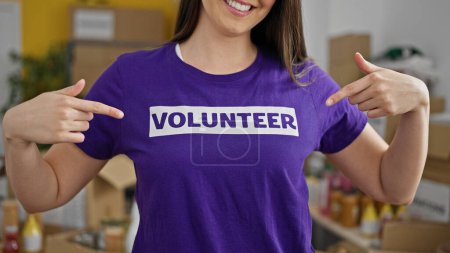 Téléchargez les photos : Jeune belle hispanique femme pointant vers uniforme bénévole au centre de charité - en image libre de droit