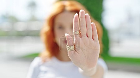 Téléchargez les photos : Jeune rousse femme faisant geste d'arrêt avec la main à la rue - en image libre de droit