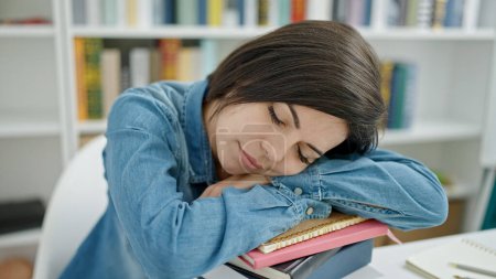 Téléchargez les photos : Jeune étudiante caucasienne dormir avec la tête sur les livres à l'université salle de classe - en image libre de droit