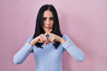 Téléchargez les photos : Hispanic woman standing over pink background rejection expression crossing fingers doing negative sign - en image libre de droit