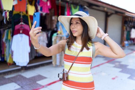 Foto de Young asian woman tourist make selfie by smartphone at street market - Imagen libre de derechos