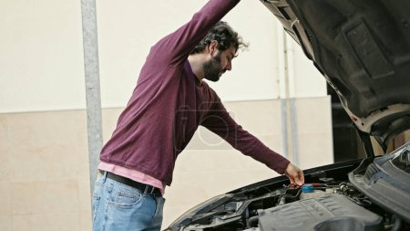 Téléchargez les photos : Jeune homme hispanique réparer voiture à la rue - en image libre de droit