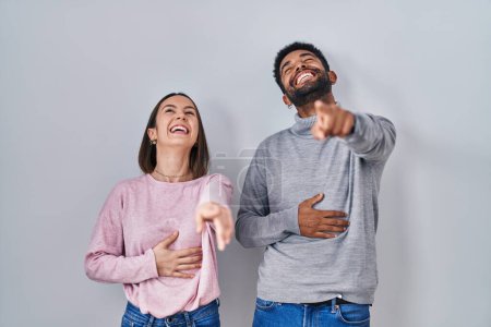 Photo for Young hispanic couple standing together laughing at you, pointing finger to the camera with hand over body, shame expression - Royalty Free Image