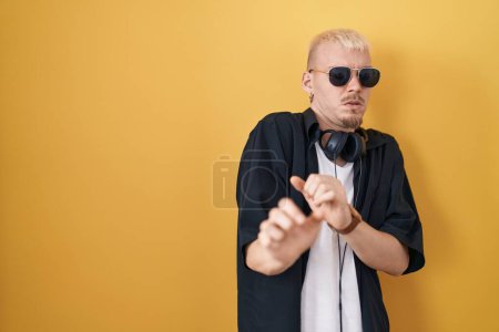 Téléchargez les photos : Jeune homme caucasien portant des lunettes de soleil debout sur fond jaune expression dégoûtée, mécontent et craintif faisant visage dégoûtant parce que réaction d'aversion. - en image libre de droit