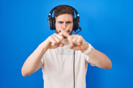 Photo for Hispanic man with beard listening to music wearing headphones rejection expression crossing fingers doing negative sign - Royalty Free Image