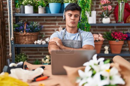 Photo for Hispanic young man working at florist shop doing video call pointing with finger to the camera and to you, confident gesture looking serious - Royalty Free Image