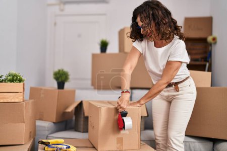 Photo for Middle age hispanic woman packing boxes at new home - Royalty Free Image
