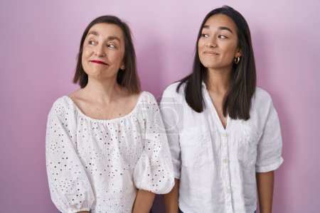 Photo for Hispanic mother and daughter together smiling looking to the side and staring away thinking. - Royalty Free Image
