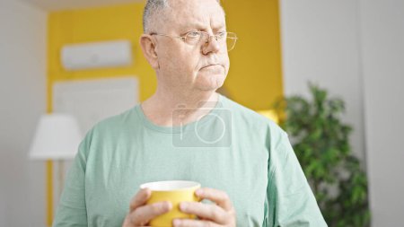 Photo for Middle age grey-haired man drinking coffee standing at home - Royalty Free Image