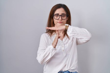 Photo for Brunette woman standing over white isolated background doing time out gesture with hands, frustrated and serious face - Royalty Free Image