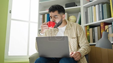Foto de Joven estudiante hispano usando laptop bebiendo café en la universidad de la biblioteca - Imagen libre de derechos