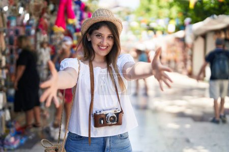 Téléchargez les photos : Jeune femme brune en vacances d'été regardant la caméra souriant à bras ouverts pour un câlin. expression joyeuse embrassant le bonheur. - en image libre de droit