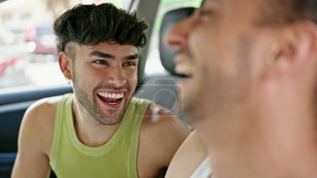 Téléchargez les photos : Deux hommes couple souriant voiture de conduite confiant parler à la rue - en image libre de droit