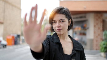Foto de Joven mujer caucásica haciendo stop gesture con la mano en la calle - Imagen libre de derechos