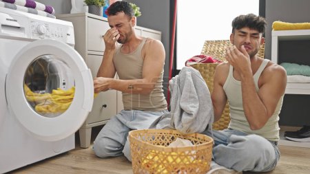 Photo for Two men couple smelling dirty clothes at laundry room - Royalty Free Image