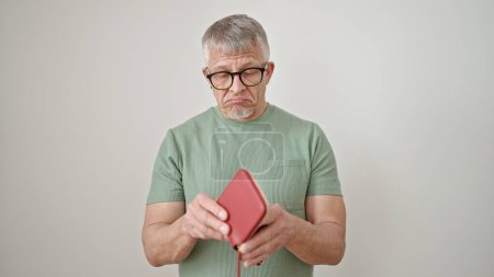 Foto de Hombre de pelo gris de mediana edad mostrando una cartera vacía sobre un fondo blanco aislado - Imagen libre de derechos