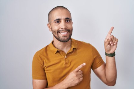 Téléchargez les photos : Homme hispanique avec barbe debout sur fond blanc souriant et regardant la caméra pointant avec deux mains et doigts sur le côté. - en image libre de droit