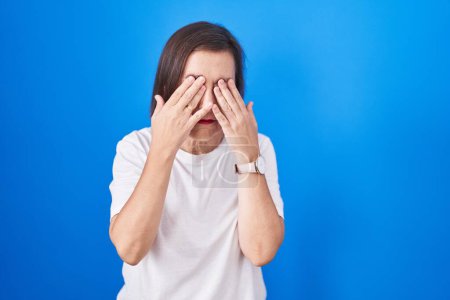 Photo for Middle age hispanic woman standing over blue background rubbing eyes for fatigue and headache, sleepy and tired expression. vision problem - Royalty Free Image