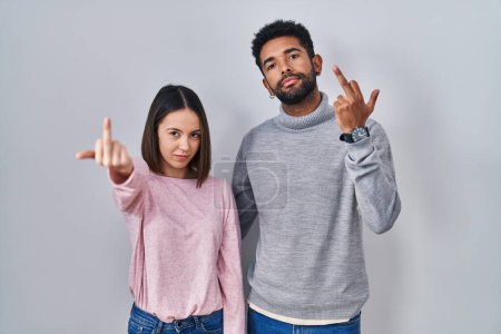 Foto de Young hispanic couple standing together showing middle finger, impolite and rude fuck off expression - Imagen libre de derechos